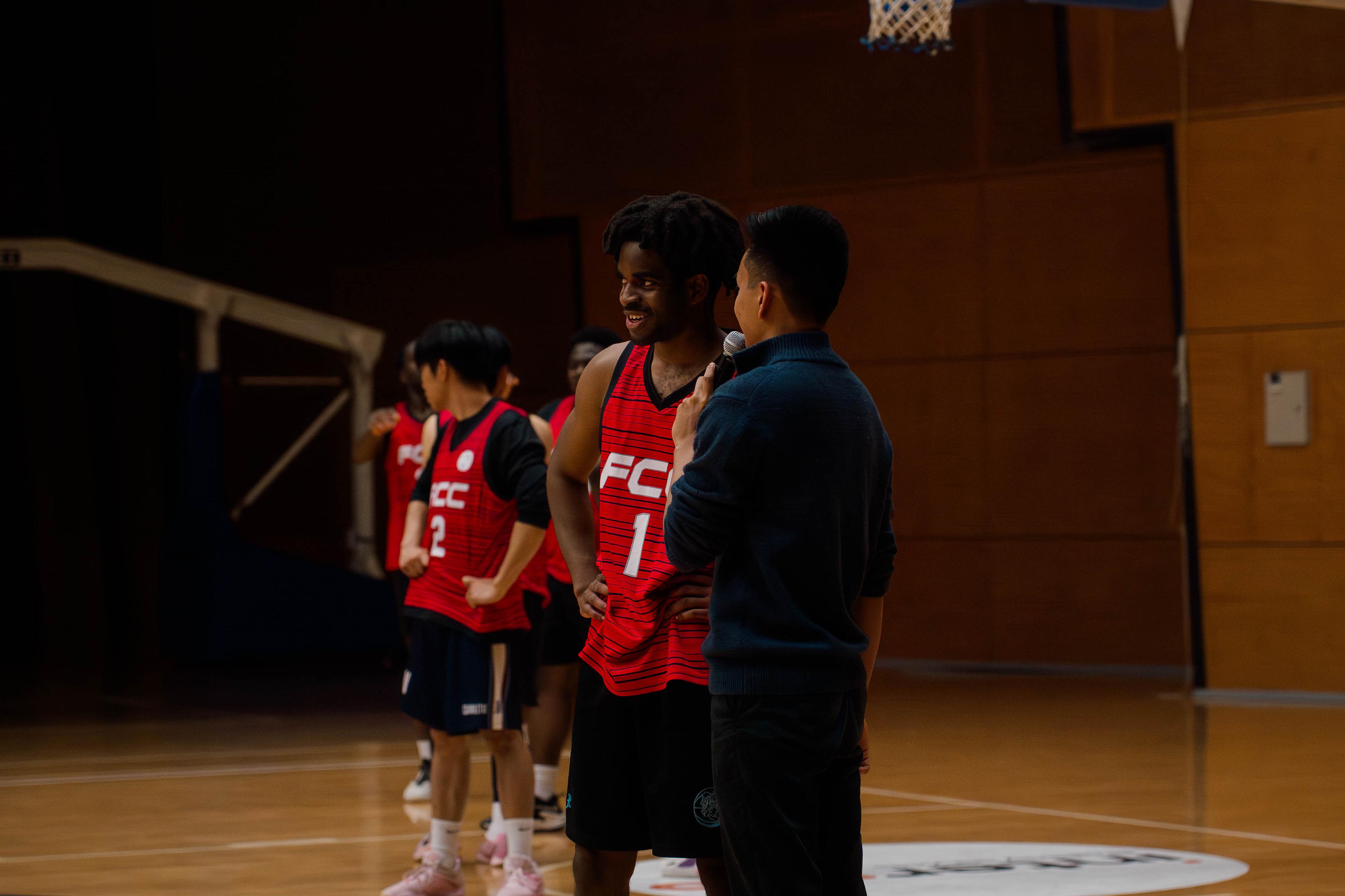 Smiling player being interviewed with a microphone courtside after a game.