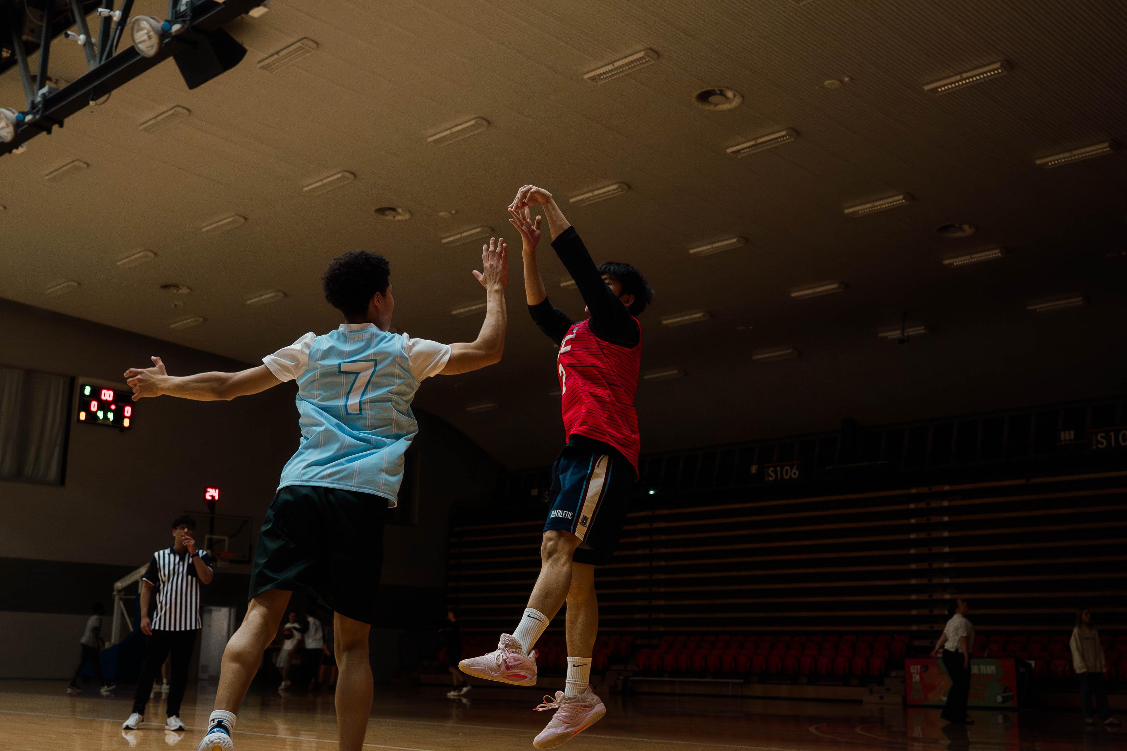Player shooting a contested jump shot over a defender during a CBL game.