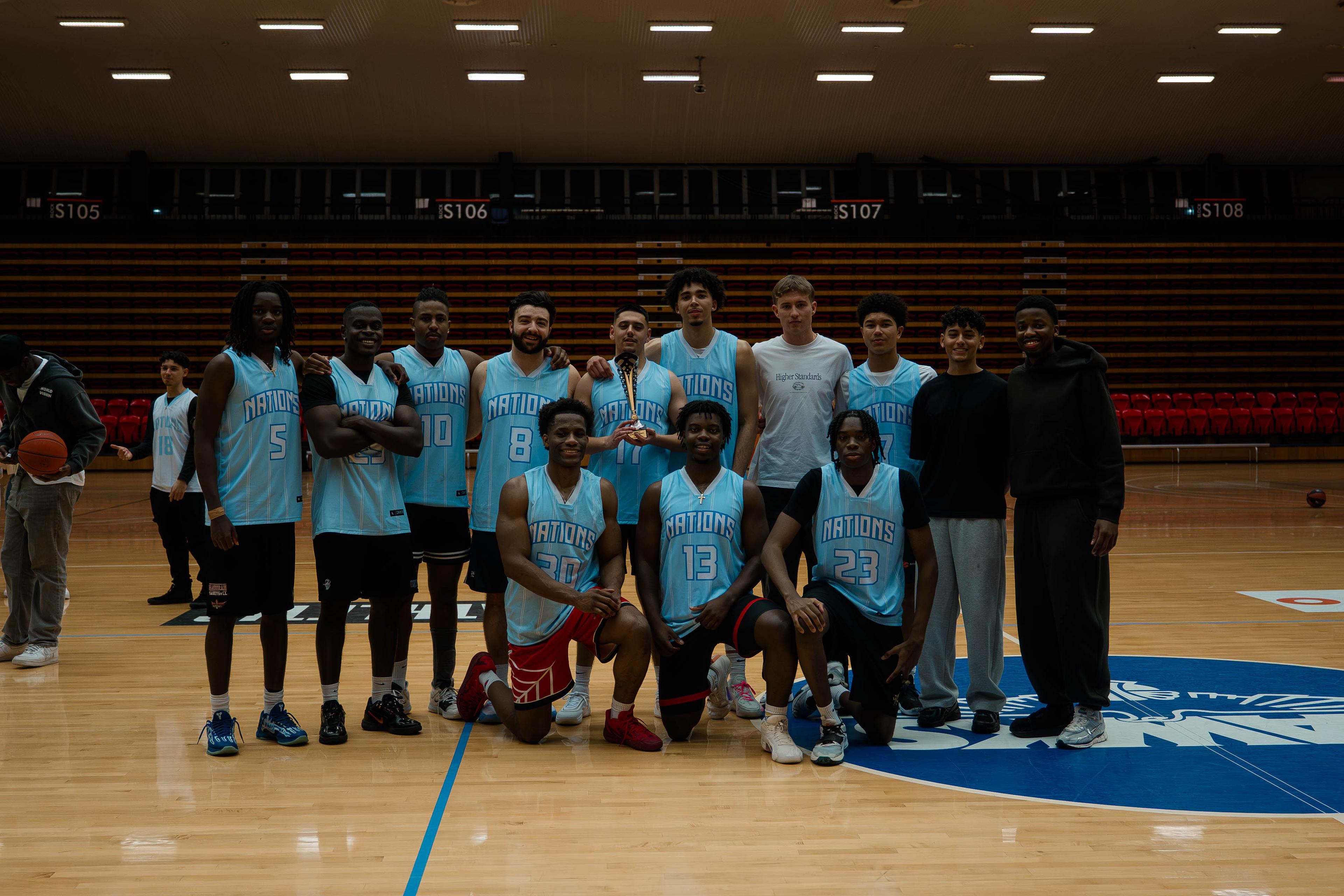 Team in light blue jerseys posing with a trophy at centre court.